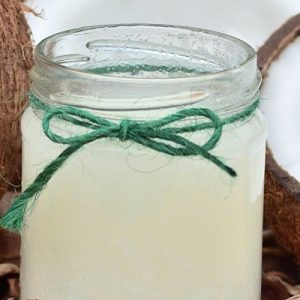 Jar of coconut oil with open fresh coconut next to it