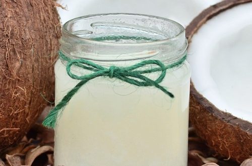 Jar of coconut oil with open fresh coconut next to it