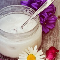 Jar of coconut oil surrounded by flowers