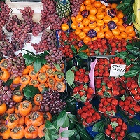 Fruit stall with colourful display of fresh healthy fruits including grapes, persimmons and strawberries