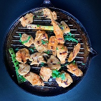 Skillet with fresh chicken pieces and some greens all lightly fried 