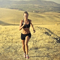 Woman smiling while going for a run in the open countryside on a sunny day