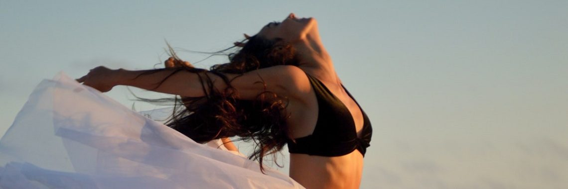 Woman dancing freely in the sunshine, creating a good dose of Vitamin D