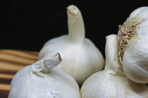 Whole garlic cloves on a wooden chopping board